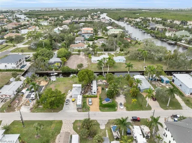Aerial view of property and surrounding area featuring nearby suburban area and a large body of water