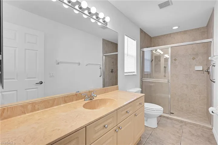 Bathroom featuring vanity, a shower stall, and light tile patterned floors