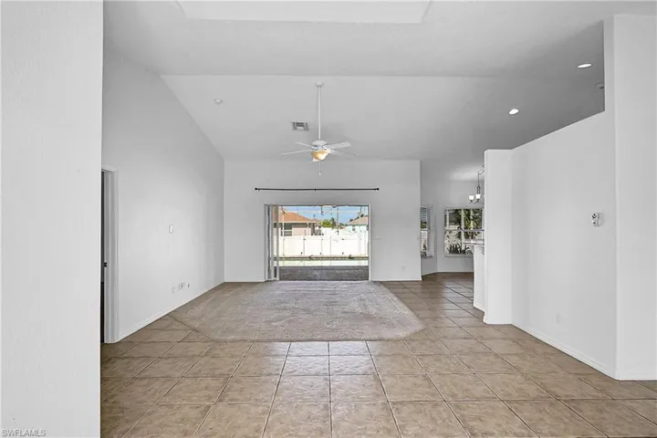 Empty room with light tile patterned floors, ceiling fan, light carpet, recessed lighting, and high vaulted ceiling