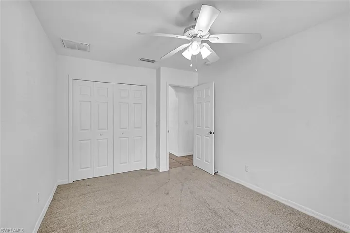 Unfurnished bedroom with light colored carpet, a closet, and ceiling fan
