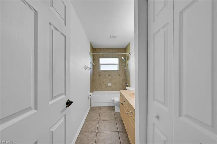 Full bath featuring vanity, a closet, shower / bathtub combination, light tile patterned floors, and a textured ceiling