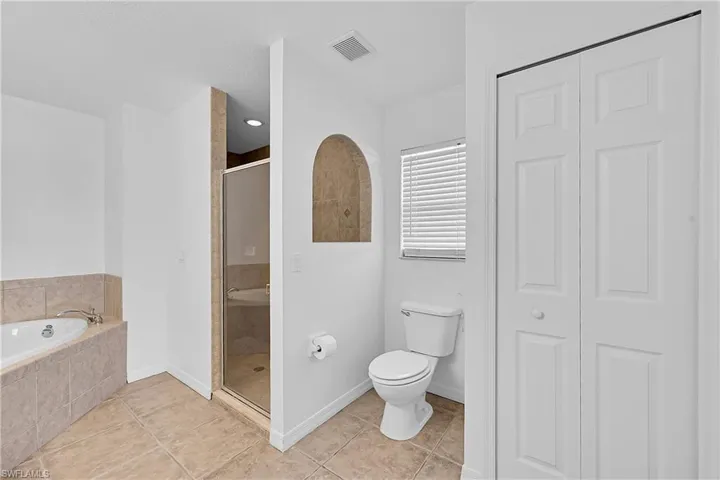 Bathroom with a closet, light tile patterned floors, a bath, and a stall shower