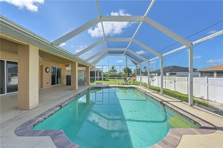 View of swimming pool with a sunroom, a ceiling fan, a patio area, and glass enclosure