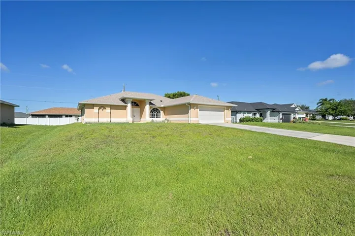 View of front of home with a front yard, driveway, an attached garage, and stucco siding