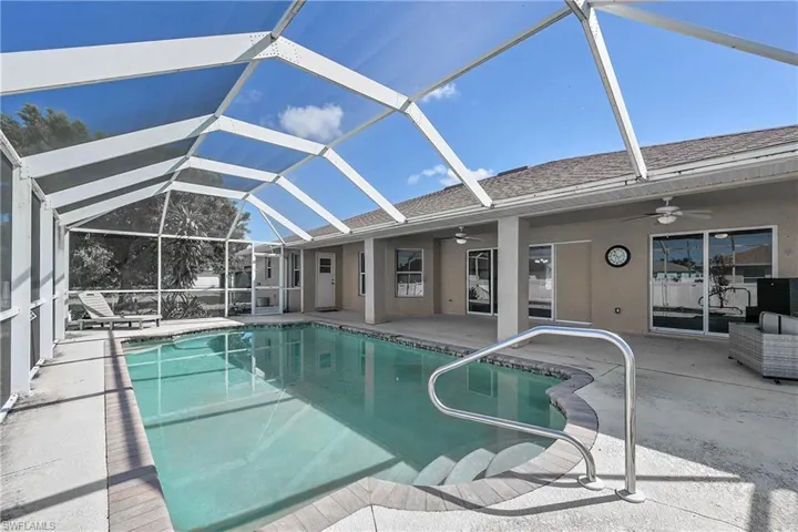 Swimming pool featuring a sunroom, a ceiling fan, a patio area, and glass enclosure