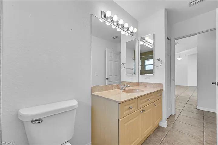 Full bathroom with vanity, light tile patterned flooring, and a textured wall