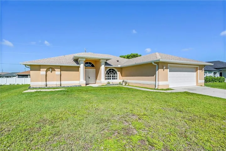 View of front of home with stucco siding, driveway, and a front lawn