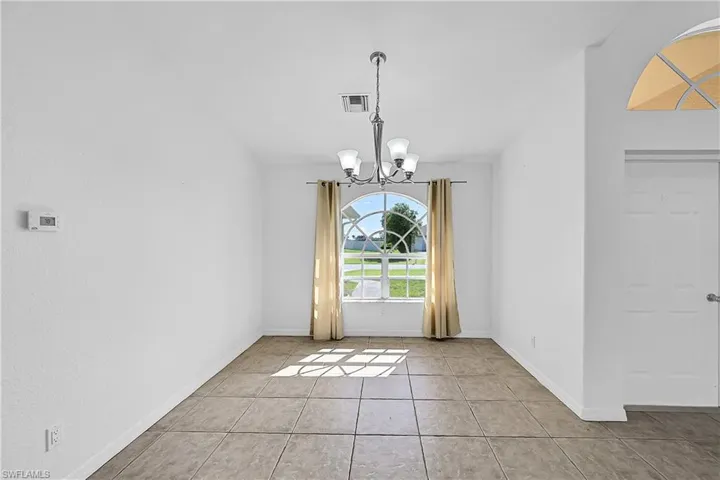 Unfurnished dining area featuring tile patterned flooring and a chandelier