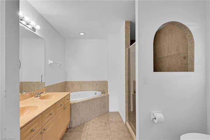 Bathroom with a garden tub, light tile patterned flooring, a stall shower, and double vanity