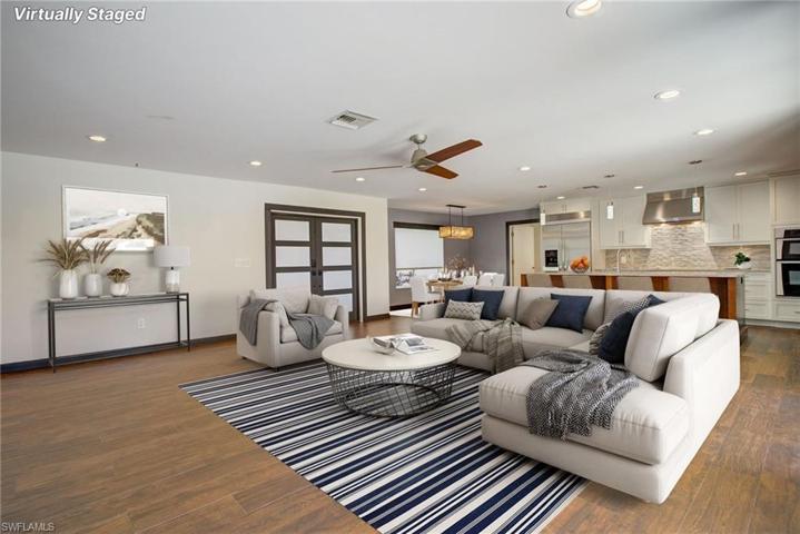 Open Floor plan Features Gorgeous Kitchen, Stainless Appliances, Large Breakfast Bar with Beautiful Cambria Quartz Counters, Recessed Lighting and Pendant lights over the Breakfast Bar, Induction Stove top and Wall ovens. This all opens to a spacious Dining room and a Huge Great-room. Rich Wood -look Tile flooring throughout the home. Two sets of Impact Sliding Glass Doors Pocket back into the walls and Create a seamless Flow to the Large Covered Lanai and on to the Brick-pavered Courtyard.