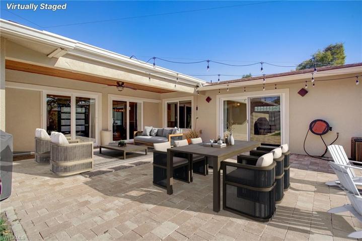 Two sets of Impact Sliding Glass Doors Pocket back into the walls and Create a seamless Flow to the Large Covered Lanai and on to the Brick-pavered Courtyard.