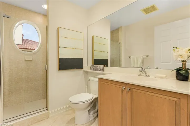 Bathroom with tile floors, an enclosed shower, toilet, and vanity with extensive cabinet space