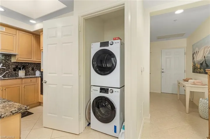 Washroom featuring stacked washer / dryer and light tile floors