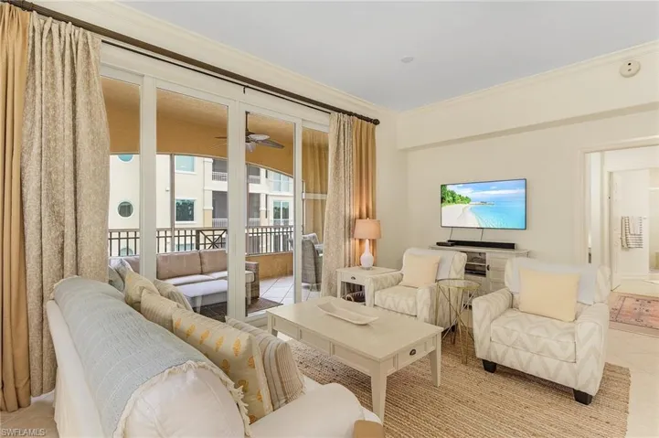 Living room with crown molding, ceiling fan, and light tile floors