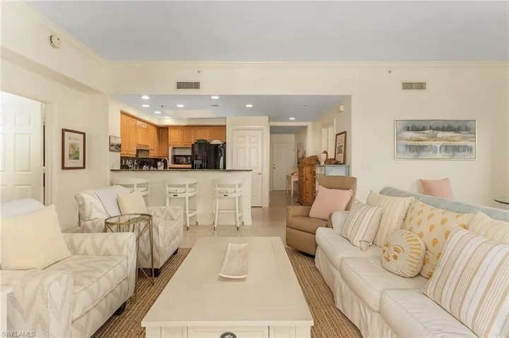Living room featuring sink, crown molding, and light tile flooring