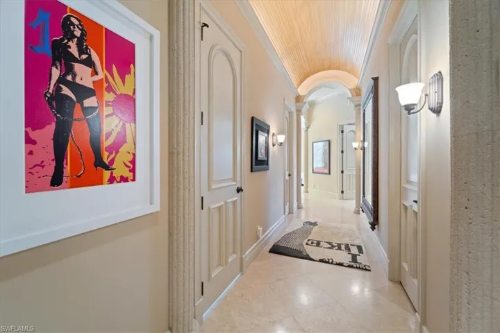 Corridor with decorative columns, lofted ceiling, tile patterned flooring, wood ceiling, and ornamental molding