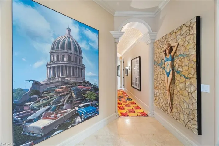 Corridor with tile patterned floors, baseboards, ornate columns, and crown molding