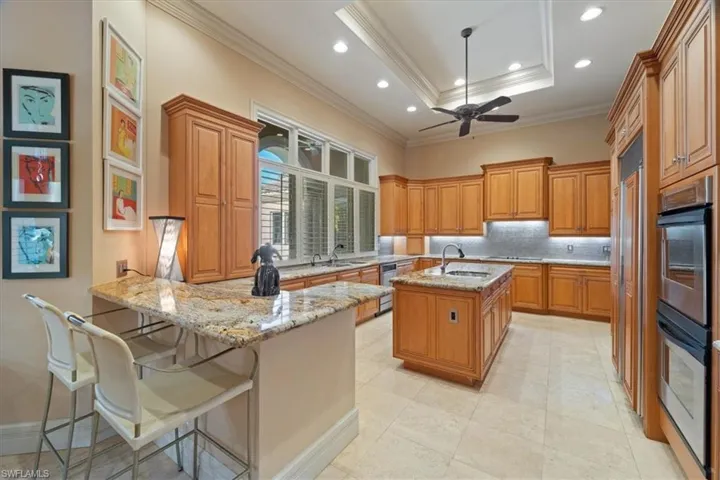 Kitchen featuring light stone counters, a sink, brown cabinetry, decorative backsplash, and a peninsula