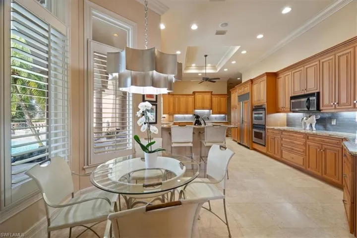 Dining room featuring ceiling fan, a raised ceiling, ornamental molding, visible vents, and recessed lighting