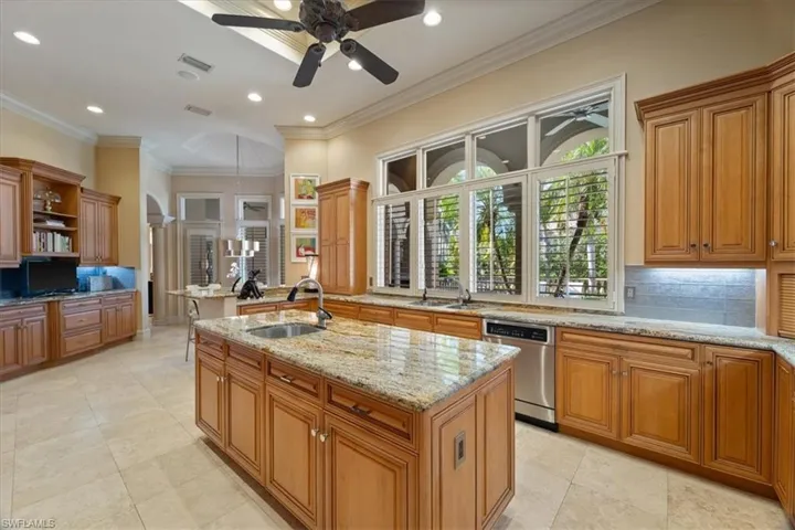 Kitchen with stainless steel dishwasher, open shelves, a sink, a kitchen island with sink, and visible vents