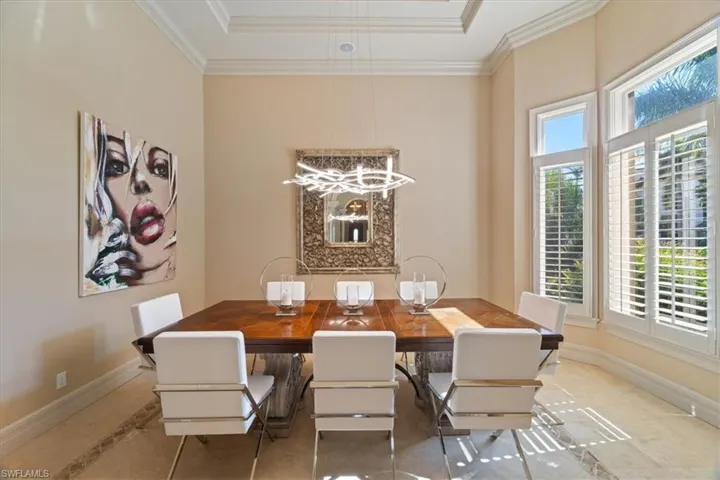 Dining room featuring a raised ceiling, baseboards, crown molding, and an inviting chandelier