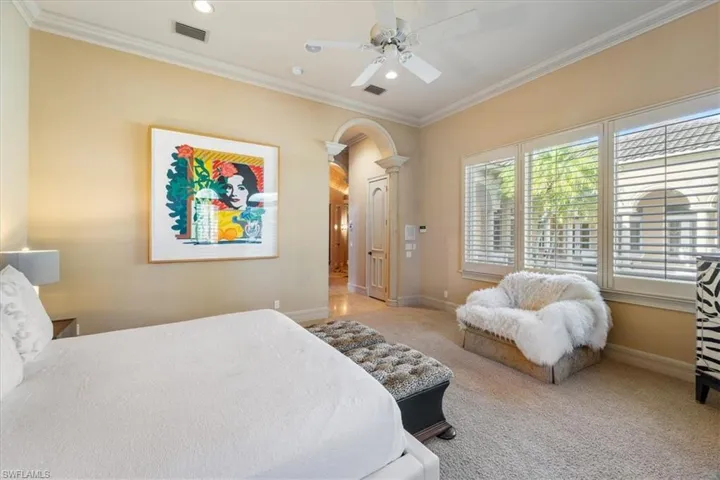 Carpeted bedroom featuring crown molding, arched walkways, ceiling fan, and recessed lighting