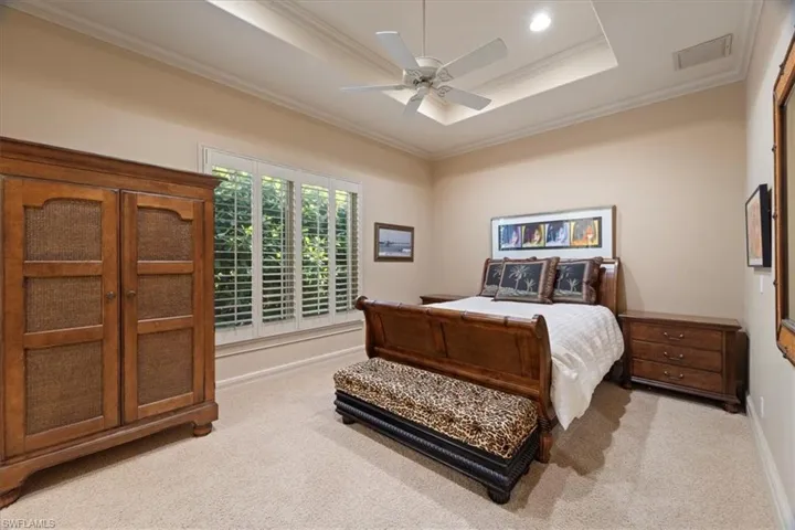 Bedroom featuring light carpet, crown molding, a tray ceiling, and visible vents