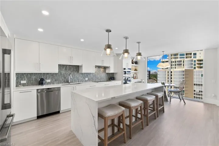 Kitchen with white cabinetry, tasteful backsplash, hanging light fixtures, appliances with stainless steel finishes, and light wood-style floors