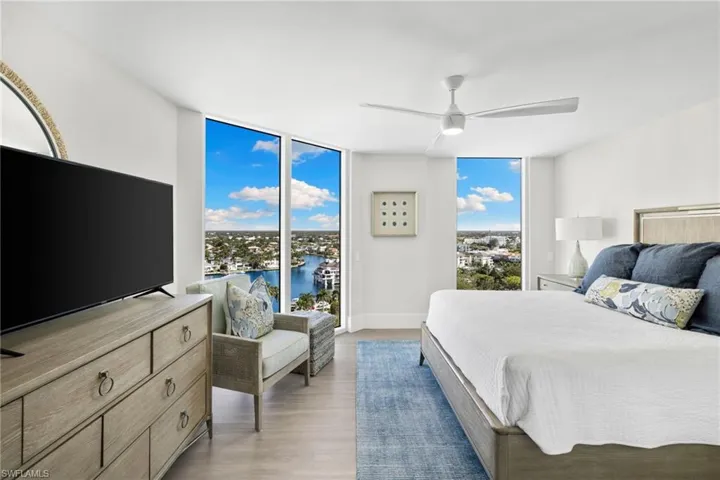 Bedroom with floor to ceiling windows, wood finished floors, a ceiling fan, and access to outside