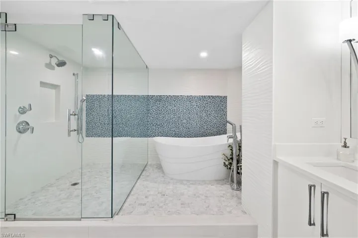 Bathroom featuring a shower stall, a freestanding bath, vanity, light tile patterned floors, and tile walls