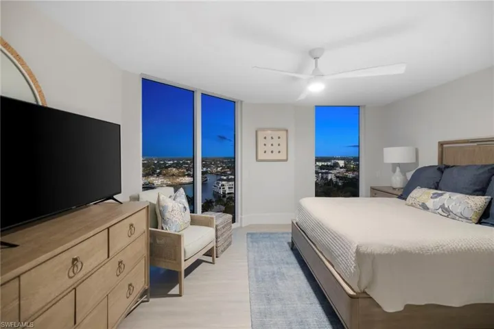 Bedroom featuring expansive windows, ceiling fan, and light wood-style flooring