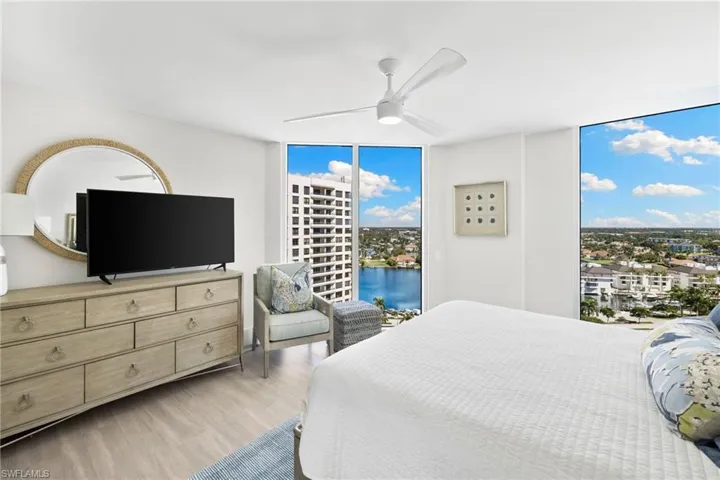 Bedroom featuring a wall of windows, multiple windows, wood finished floors, a ceiling fan, and access to exterior