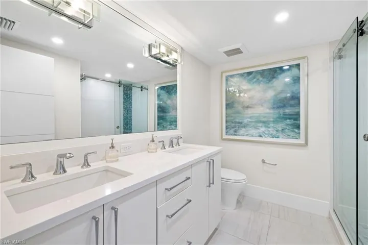 Bathroom with a stall shower, double vanity, and recessed lighting