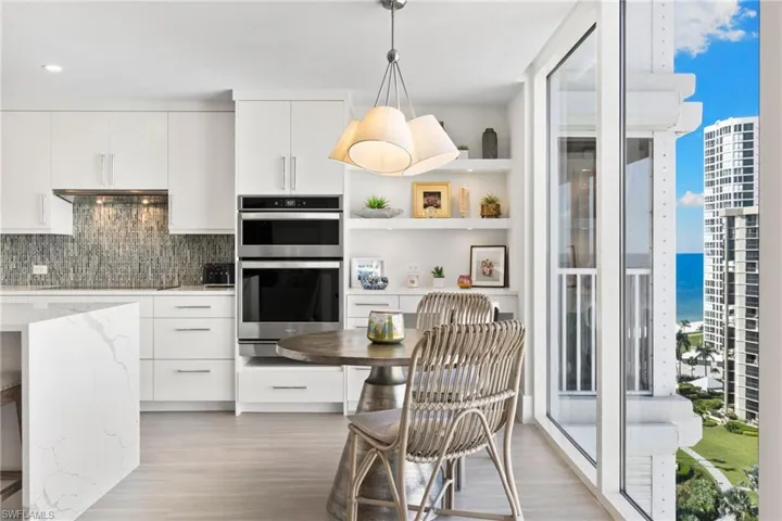 Kitchen with white cabinetry, modern cabinets, stainless steel double oven, and hanging light fixtures