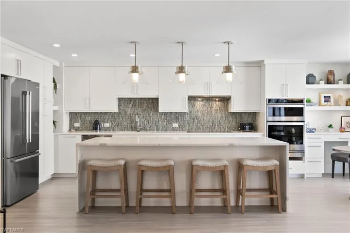 Kitchen with open shelves, white cabinets, a kitchen breakfast bar, stainless steel appliances, and recessed lighting