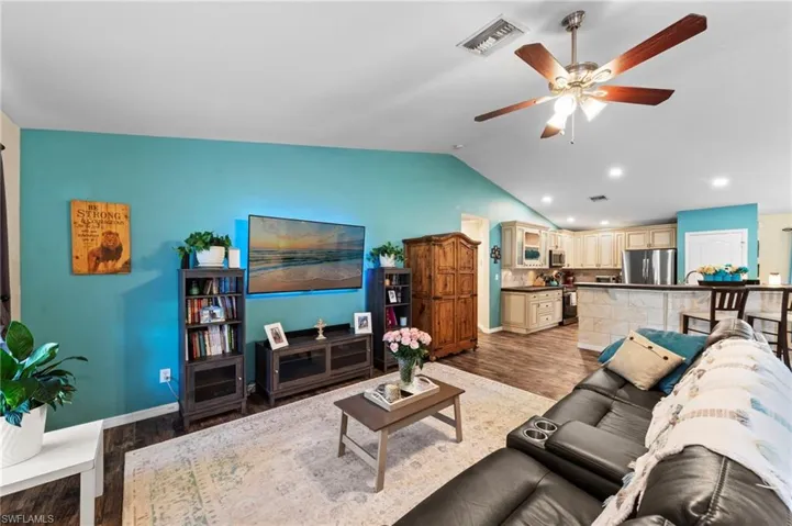 Open-concept living room featuring luxury vinyl plank flooring installed in 2021 and vaulted ceilings