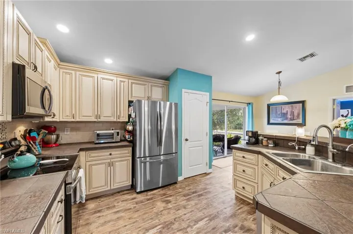 Gorgeous kitchen featuring upgraded cabinets, tumblestone backsplash, cabinet lighting, a tiled island with barstool seating and Samsung stainless steel appliances purchased in 2022