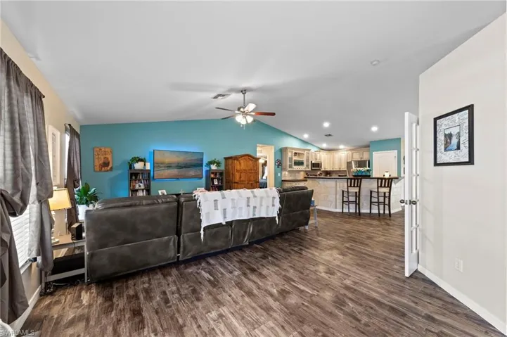 Open-concept living room featuring luxury vinyl plank flooring installed in 2021 and vaulted ceilings
