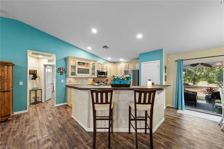 Gorgeous kitchen featuring upgraded cabinets, tumblestone backsplash, cabinet lighting, a tiled island with barstool seating and Samsung stainless steel appliances purchased in 2022