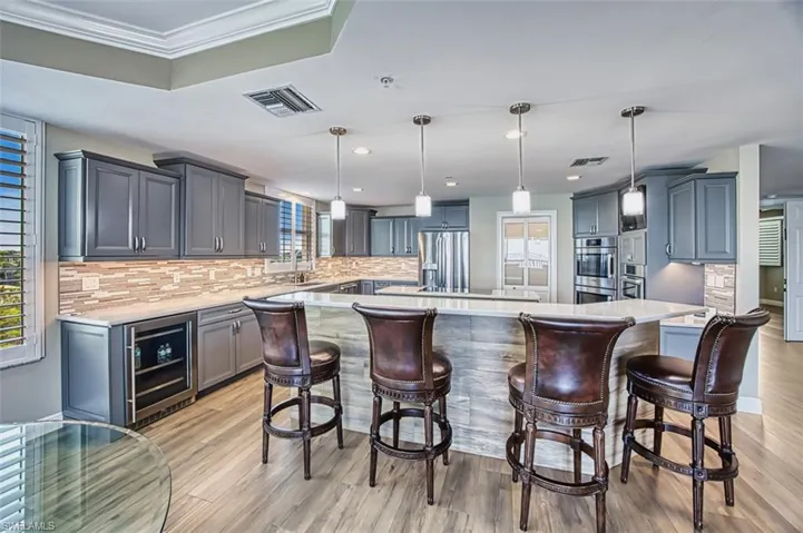 Kitchen featuring pendant lighting, a breakfast bar, beverage cooler, a kitchen island, and recessed lighting
