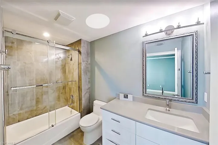 Full bath with enclosed tub / shower combo, vanity, and recessed lighting