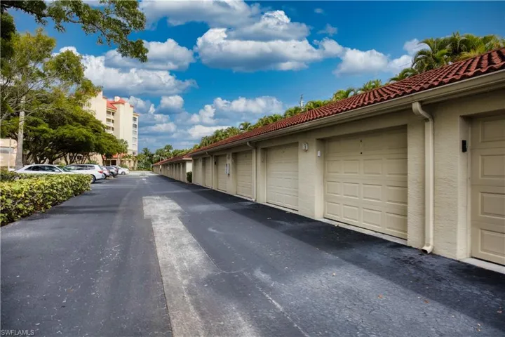 View of asphalt road featuring community garages