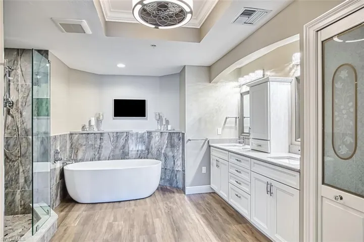 Full bathroom with a freestanding bath, a marble finish shower, double vanity, tile walls.
