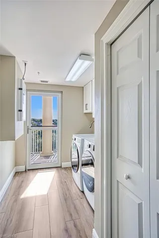 Laundry room featuring wood tiled floors, washer and clothes dryer, and cabinet space