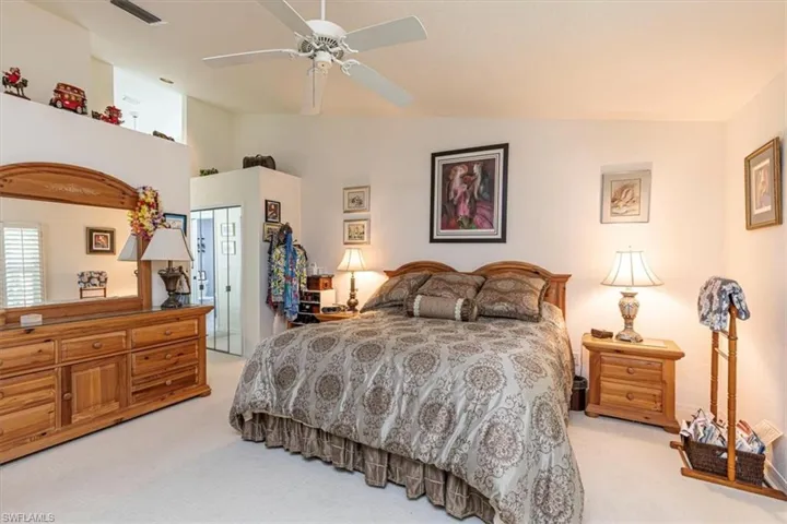 Bedroom with ceiling fan, light colored carpet, a closet, and high vaulted ceiling