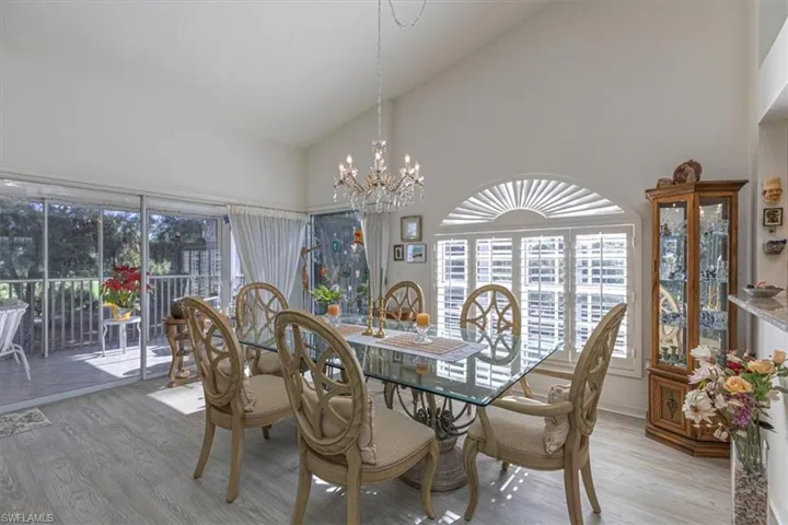 Dining room with wood finished floors, high vaulted ceiling, and a chandelier