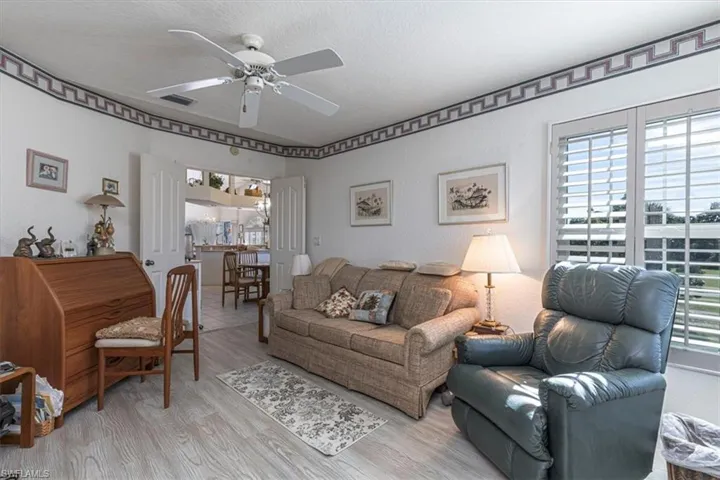 Living room with wood finished floors, ceiling fan, healthy amount of natural light, and a textured ceiling