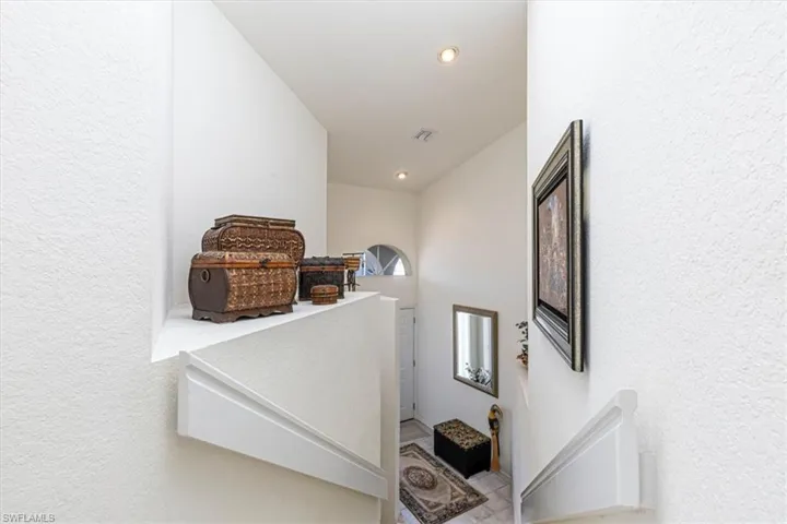 Hall featuring a textured wall, an upstairs landing, and recessed lighting