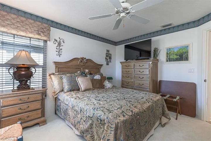 Bedroom with a textured ceiling, light carpet, and ceiling fan