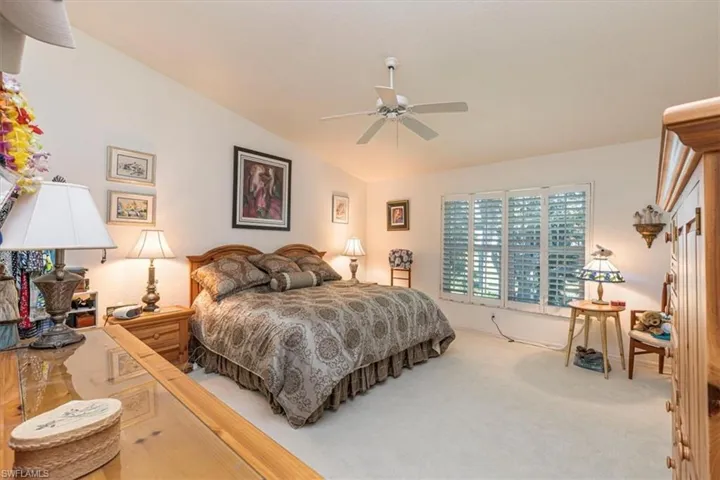 Carpeted bedroom featuring ceiling fan and vaulted ceiling